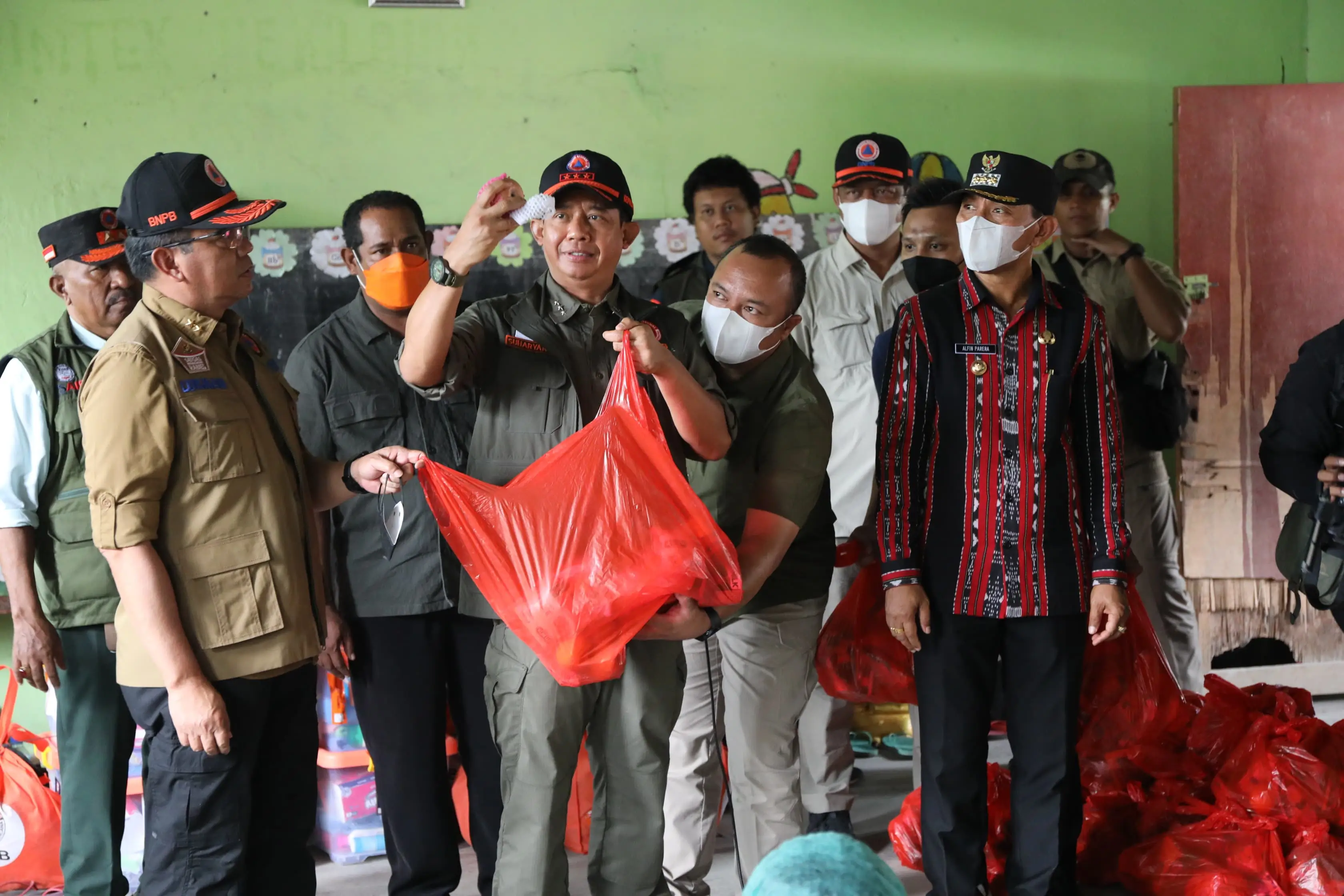 Kepala Badan Nasional Penanggulangan Bencana (BNPB) Letjen TNI Dr. Suharyanto, S.Sos., M.M (kemeja dan rompi hijau) saat memberikan bantuan kepada pengungsi yang berada di Desa Hikong, Kabupaten Sikka, Nusa Tenggara Timur pada Jumat (8/11).